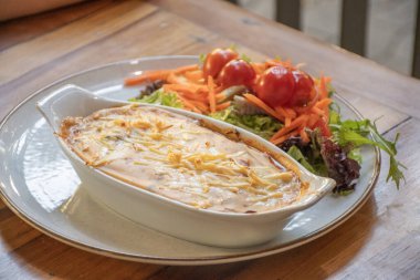 Vejetaryen yemeği keçi peynirli graten ve kiraz domatesli salata rendelenmiş havuç ve marul.