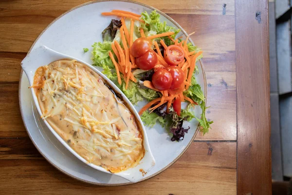 tasty vegan dish of aubergine au gratin with goat cheese and salad with cherry tomatoes grated carrot and lettuce top view