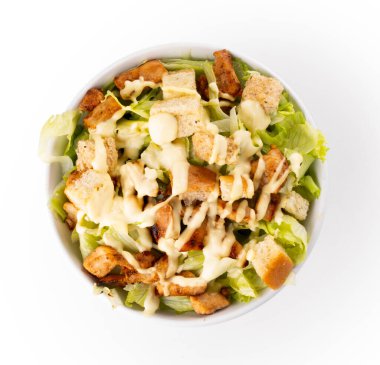 Bir kase marul yaprağı salatası, kıtır ekmek ve sezar soslu üst manzara izole edilmiş.