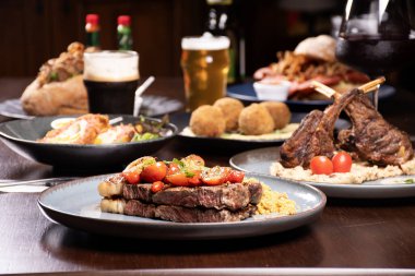 Biftek lokantasında bir ziyafet masası. Odak noktasında sığır eti, odak noktasında kuzu pirzolası ve diğer yemeklerle birlikte.