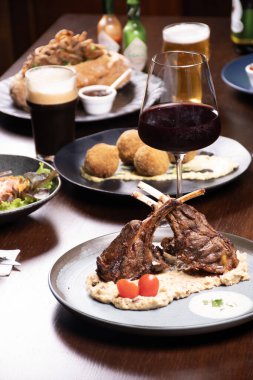 Biftek evindeki ziyafet masasında patates püresi ve bir bardak kırmızı şarapla kuzu pirzolası.