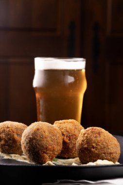 Kızarmış balık keki aperatifi. Barda yarım litre balık birası ve somon balığı.