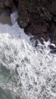 Deniz dalgaları ve köpüklü kaya kumsalının drone görüntüsü. Yüksek kalite 4k görüntü