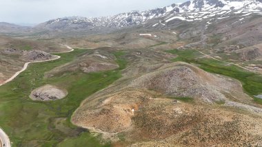 Dağ yeşili manzara. Ufuktaki ilk çimenlikte, karla kaplı dağları sersemleten doğa. Yüksek kalite fotoğraf