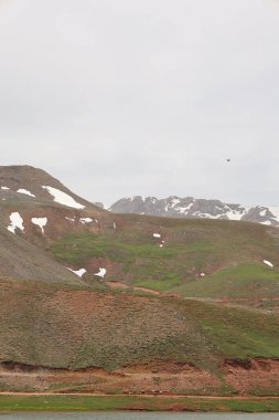 Dağ yeşili manzara. Ufuktaki ilk çimenlikte, karla kaplı dağları sersemleten doğa. Yüksek kalite fotoğraf