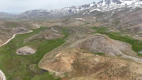 Dağ yeşili manzara. Ufuktaki ilk çimenlikte, karla kaplı dağları sersemleten doğa. Yüksek kalite fotoğraf