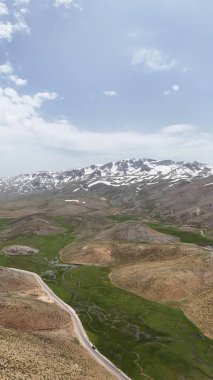 Dağ yeşili manzara. Ufuktaki ilk çimenlikte, karla kaplı dağları sersemleten doğa. Yüksek kalite fotoğraf