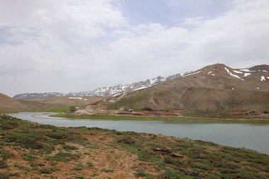 Dağ yeşili manzara. Ufuktaki ilk çimenlikte, karla kaplı dağları sersemleten doğa. Yüksek kalite fotoğraf