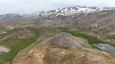 Dağ yeşili manzara. Ufuktaki ilk çimenlikte, karla kaplı dağları sersemleten doğa. Yüksek kalite fotoğraf