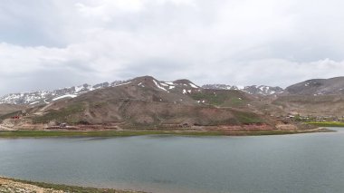 Dağ yeşili manzara. Ufuktaki ilk çimenlikte, karla kaplı dağları sersemleten doğa. Yüksek kalite fotoğraf