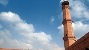 Arka planda bulutlu gökyüzü olan badshahi camii minaresi