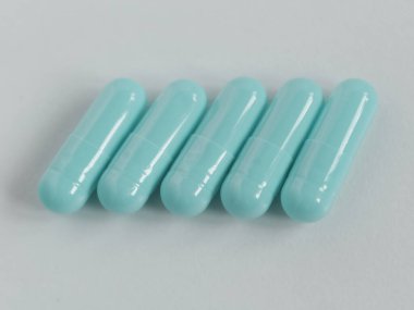 Beyaz arkaplandaki beş kapsül hapını kapat