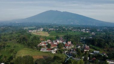 Dağlık bir arka planı olan bir evin insansız hava aracı videosu. Düz bir hareketle çekilmiş ve kamera ileriye bakıyor.