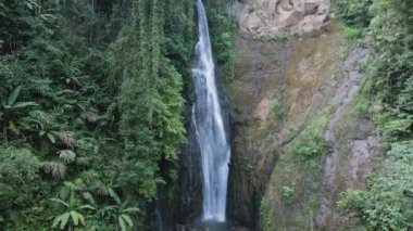 Dağlardaki şelalenin insansız hava aracı videosu. İHA aşağı iniyor ve kamera doğruca şelaleye bakıyor.