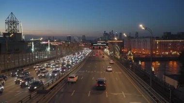 Moskova Nehri 'nin karşısındaki büyük bir caddede akşam trafiği. Arka planda Moskova, Rusya. (tahtadaki yazıt: Sürücüler, hız kipine dikkat edin) 