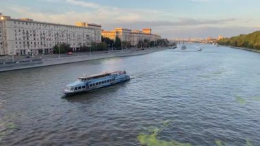 Moskova Nehri boyunca yüzen bir turist teknesinin arka planında Stalin dönemi binaları, Moskova, Rusya 