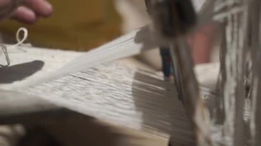 Yaşlı bir adam ustalıkla eski antika ahşap dokuma tezgahını kırsal bir ortamda ustalıkla örüyor ve karmaşık desenler oluşturuyor. Ladakh, Hindistan