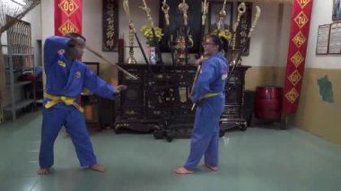 Geleneksel Vietnamlı Dövüş Sanatları Sanatçısı Vovinam sanatçıları geleneksel bir Vietnam tapınağında titizlikle ve disiplinle sopa dövüşü yapıyorlar..
