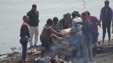 Erkekler, Manikarnika Ghat 'ın merdivenlerindeki ölü yakma odununa koyuyor. Varanasi, Hindistan