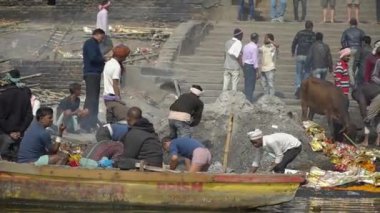 Erkekler kül yığınlarında mücevher arıyor ve Manikarnika Ghat 'ın merdivenlerinde kalıntılar arıyor. Varanasi, Hindistan