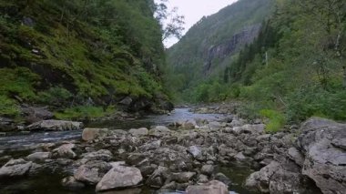 İnsansız hava aracı Norveç 'teki kayalık bir dağ nehrinin üzerinden alçaktan uçuyor.