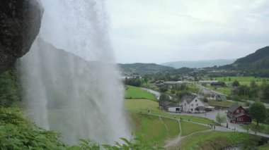 Steinsdalsfossen şelalesi arka planda bir Norveç köyünün üzerine su sıçratıyor.