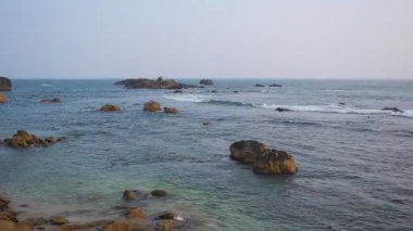 Gün batımında Sri Lanka 'daki sakin okyanus sahilinde kayalara çarpan dalgalar.