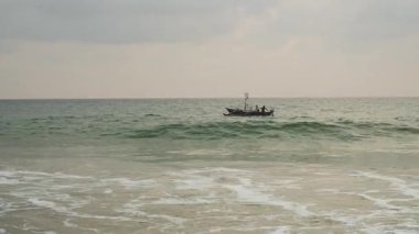 Gün batımında Sri Lanka 'nın canlı sularında bir teknede çalışan balıkçılar.
