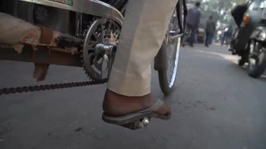 Yoğun bir Delhi caddesinde yayalarla pedal çeviren bir bisikletçinin yakın çekimi.