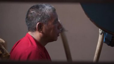 Ladakh 'taki Budist keşiş iki tokmakla büyük bir davul çalıyor.