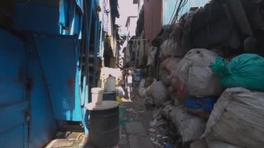 Mumbai Dharavi gecekondu mahallesinde bir adam yürüyor.