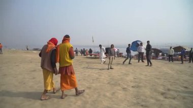 Turuncu elbiseli adam büyükbabasını Ganj nehrinde taşıyor.