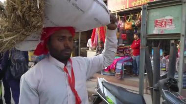 Hintli hacı Varanasi 'de kalabalık bir caddede bir çuval taşıyor.