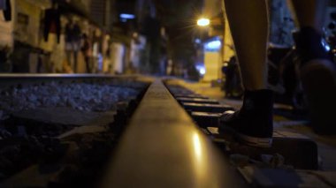 People walks along Hanoi railway tracks at night low angle view
