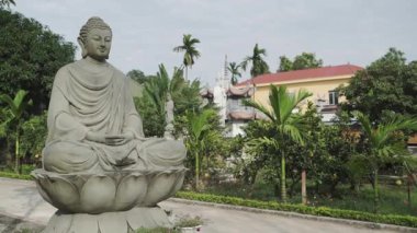 Sitting Buddha statue in a Vietnam garden with a building in the background