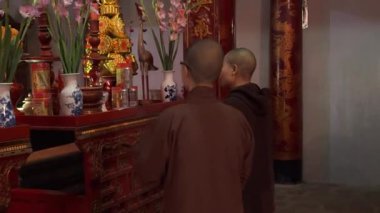 Cüppeli iki keşiş Vietnam tapınağında mihrabın önünde tekrar tekrar eğiliyor.
