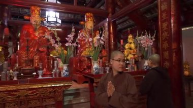 Hue Thien Mu tapınağının iç kısımlarında iki rahip kırmızı sunakta dua ediyor.