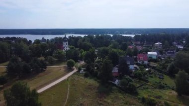 Letonya 'da bir kilise, evler ve gölü olan küçük Baltezer kasabasının hava manzarası.