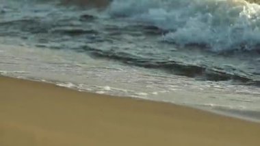 Dalgalar gün batımında Baltık Denizi 'nin kumlu kıyılarını nazikçe dolaşır.