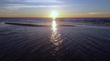 Baltis denizi, dalgalar ve uçan kuşlar üzerinde gün batımının havadan görüntüsü