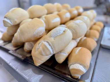 Bir fırın ortamında yeni pişmiş Fransız ekmeği yığını. Geleneksel zanaatkar ekmeğinin altın kabuğunu ve yumuşak iç yüzünü sergiliyor. Metal bir tepside dikkatlice sıralanmış..