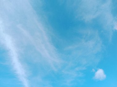 Açık mavi gökyüzü ve birkaç bulut. Gökyüzü çok parlak ve bulutlar etrafa saçılmış.