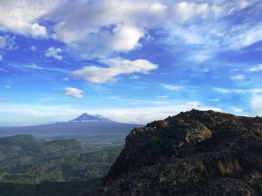 Capture the awe-inspiring beauty of Mount Merapi, an active volcano in Central Java, Indonesia. This stunning photograph showcases the dramatic contrast between the rugged volcanic landscape and the serene blue sky. Perfect for nature lovers, travel  clipart