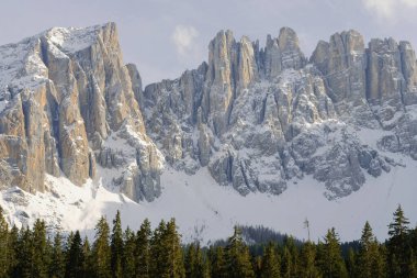 Arkasında karla kaplı dağ zirveleri olan dağlık dağlarla çevrili kayalık bir sıradağ.