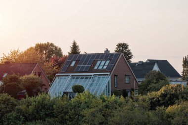 Çatıda güneş panelleri olan ev. Doğa tarafından üretilen enerji. Güneş enerjisi üretiyor. Kırsal kesimdeki özel evde fotovoltaik sistemler. Yarı iletken teknoloji. Karbon ayak izi azaltma.