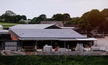 Çatıda güneş panelleri olan bir depo. Doğa tarafından üretilen enerji. Güneş enerjisi üretiyor. Kırsaldaki ahır evinin fotovoltaik sistemleri. Yarı iletken teknoloji. Karbonsuz ayak izi.