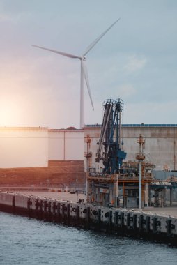 Sürdürülebilir enerji çözümleri olan LNG terminali. İskelede rüzgar jeneratörü var. Sürdürülebilir iş kavramı.