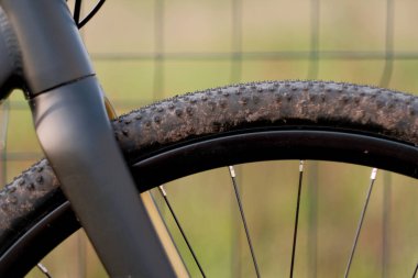 Side view of the head tube and carbon fork of the bicycle with dirty tires and spokes. clipart