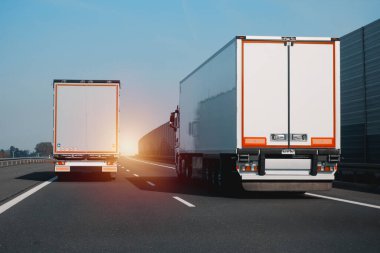 Otobanda birbirini sollayan ve sollayan iki modern yarı karavan kamyonu. Nakliye ve posta teslimatı için ticari araç. Malların kapı kapı dolaşımı.
