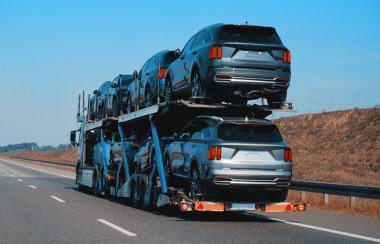 Satılık yepyeni SUV arabaları olan bir karavan kamyonu. Yeni araba teslimatı ve nakliyat. Araba taşıyıcı karavanı müşteriler için bir sürü yeni arabayla dolu. İki seviye modüler hidrolik yarı römork